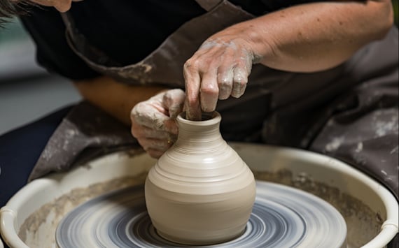 En krukkemager drejer en krukke i ler