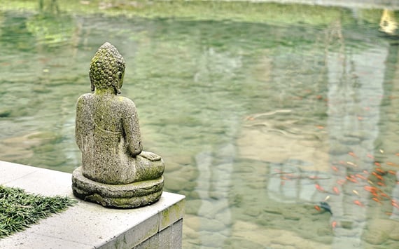 Statue der i ro ser ud over vandet. I behandling med akupunktur er et af målerne at gennem at behandle kroppen, at opnå ro, afspænding og frihed fra stress.
